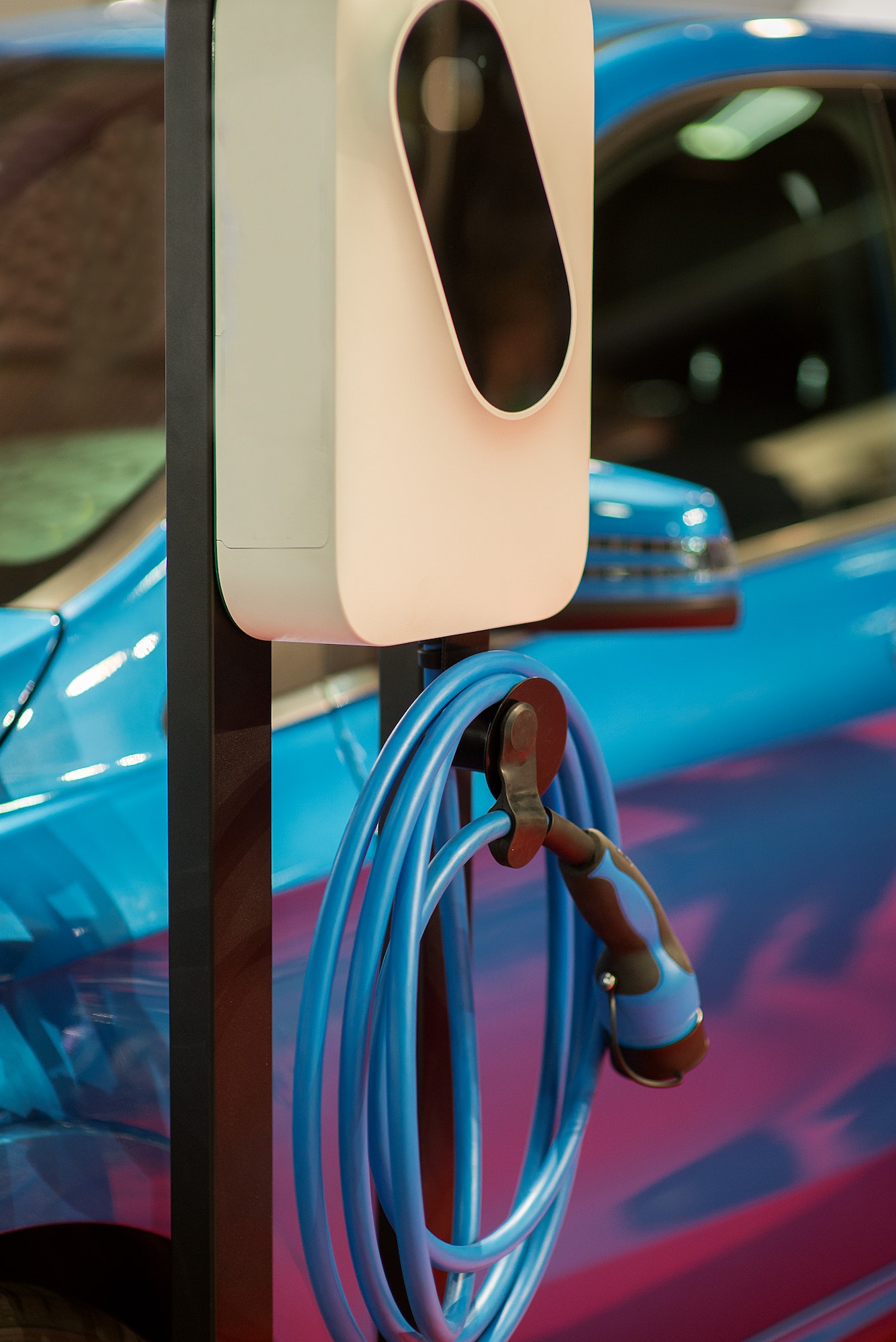 EV Car or Electric car at charging station with the power cable supply plugged in on blurred Night